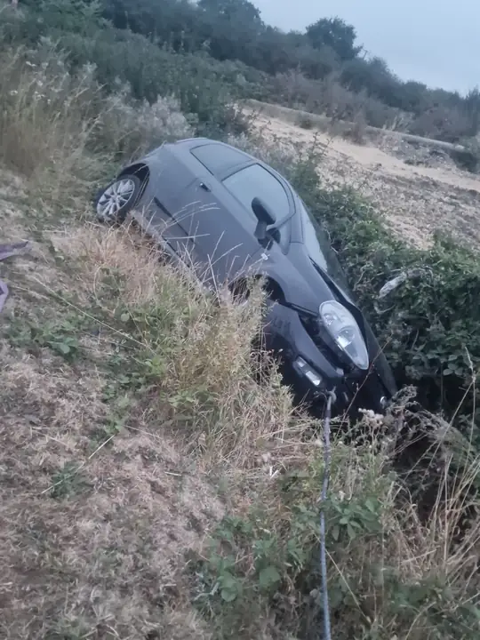 Car halfway down a bank, winch line on